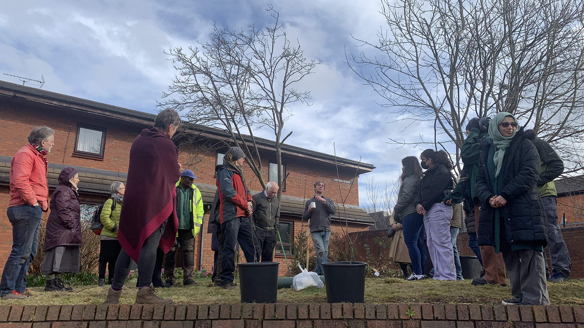 Derren Creswell standing with trees gifted to Our Garden and people listening